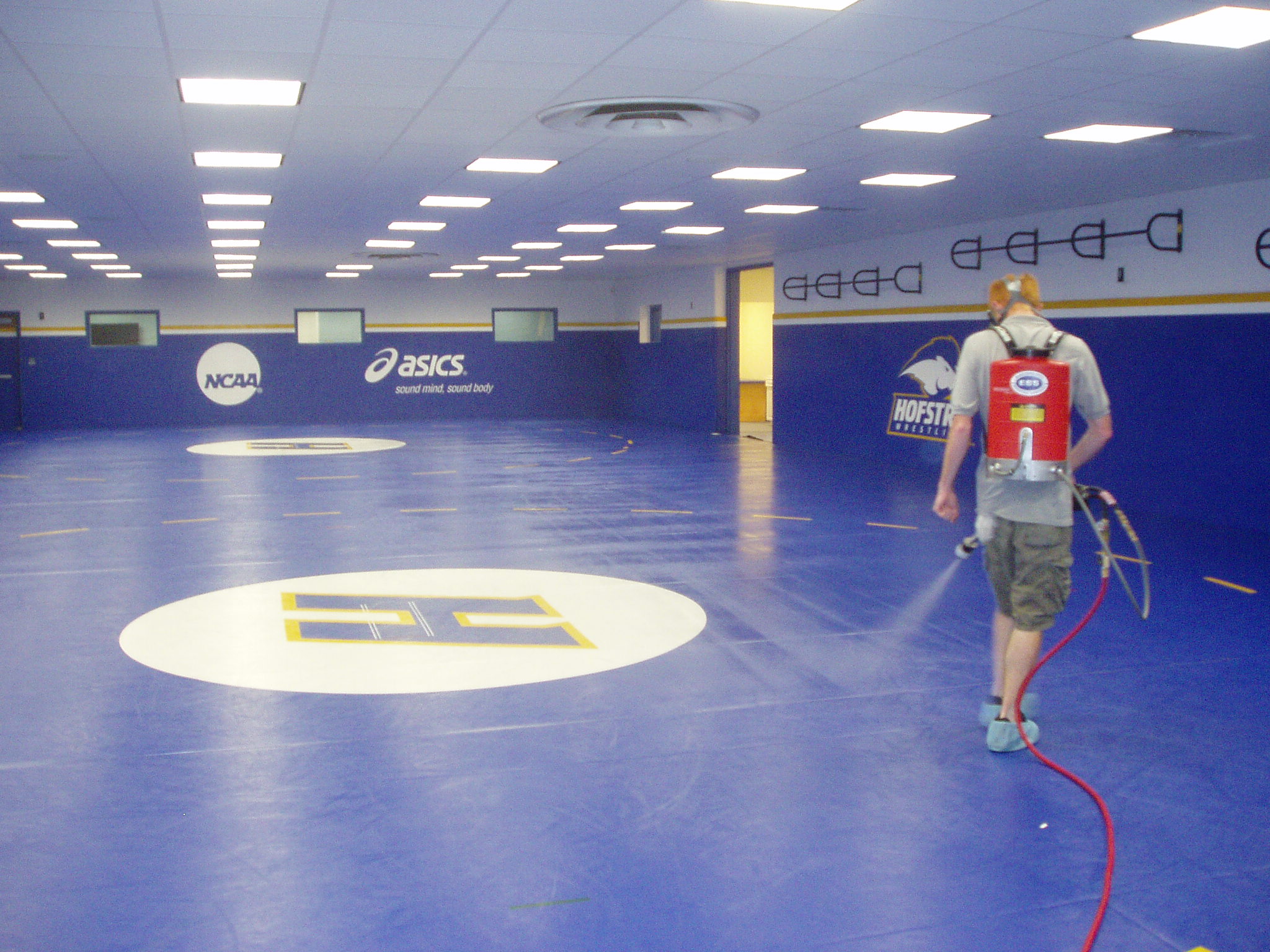SaniTech technician spraying antimicrobial solution at Hofstra University wrestling facility
